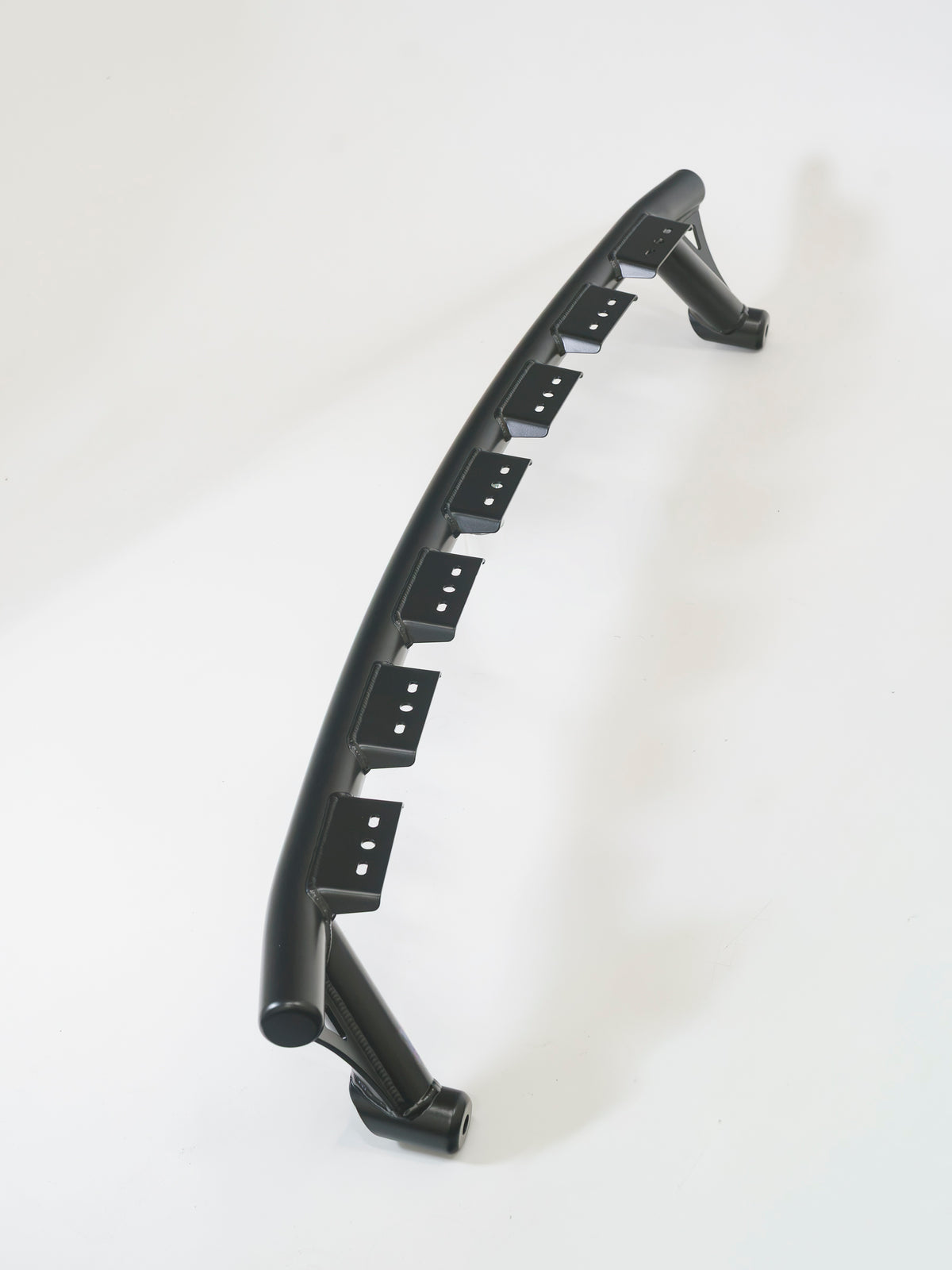 Black curved Lewis Built Performance APEX Ford Super Duty bumper light mount with multiple mounting slots on a white background.