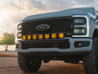 Leveled gray Ford Super Duty at sunset featuring the Lewis Built Performance APEX bumper light mount with seven bright amber auxiliary lights.