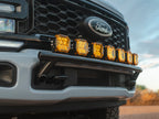 Close-up of a leveled gray Ford Super Duty front grille and bumper featuring seven amber LED lights mounted on a black Lewis Built Performance APEX light mount below the grille.