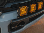 Close-up of seven amber LED off-road lights mounted on a black Lewis Built Performance APEX light mount on the front bumper of a leveled gray Ford Super Duty.