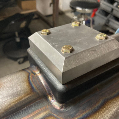 Close-up of a bumstop pad on a trophy truck rear axle housing being tig welded on.